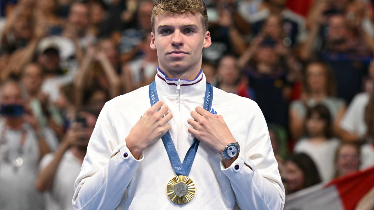 Gold medallist France's Leon Marchand stands on the podium of the men's 200m butterfly swimming event during the Paris 2024 Olympic Games at the Paris La Defense Arena in Nanterre, west of Paris, on July 31, 2024. (Photo by Jonathan NACKSTRAND / AFP)