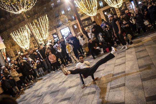 PARIS, FRANCE - DECEMBER 25: A breakdancer performs a street show at the Champs-Elysees as the people celebrate Christmas ahead of the New Year's eve in Paris, France on December 25, 2023. (Photo by Bruno Thevenin/Anadolu via Getty Images)