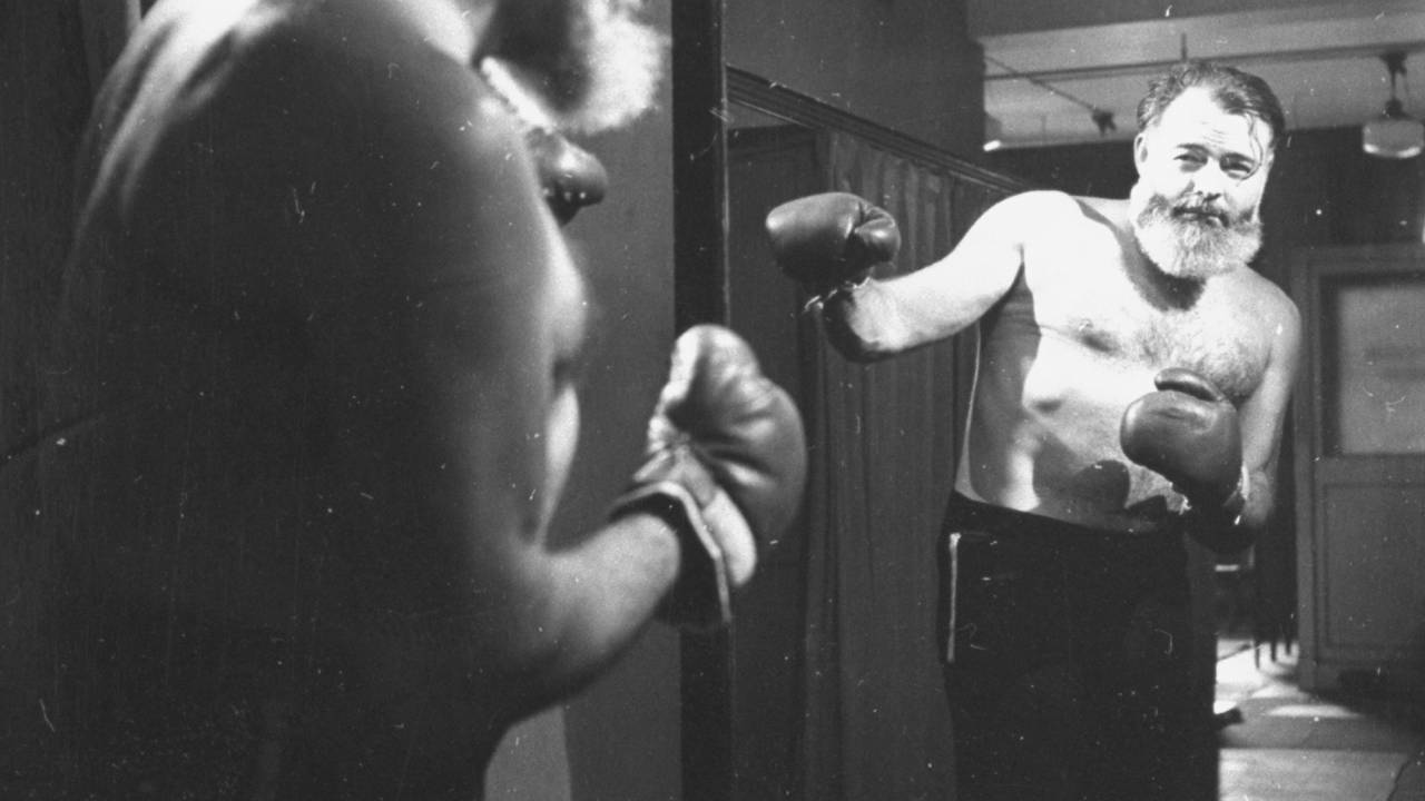 Author Ernest Hemingway standing bare-chested sparring in front of mirror. (Photo by George Karger/Getty Images)
