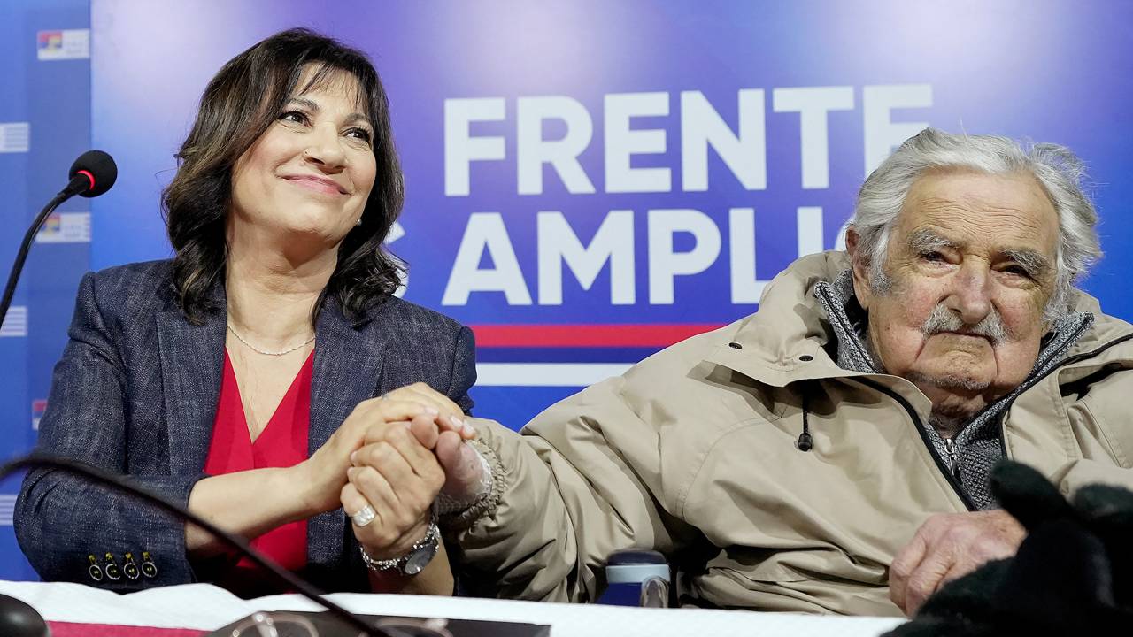 Picture released by adhoc news agency showing Uruguayan journalist and writer Blanca Rodriguez (L), holding the hand of former Uruguayan President Jose Mujica, during a press conference to present her formal entry into the Frente Amplio (FA) leftist political coalition, for which she will run for the Senate under Mujica's MPP party, at the FA's headquarters in Montevideo on August 27, 2024. Former Uruguayan President Jose Mujica returned home on Tuesday after being hospitalized for 24 hours for a deterioration of his kidney function due to the oncological treatment he received, but he is fragile, his personal doctor said. (Photo by Javier Calvelo / adhoc / AFP) / - Uruguay OUT / RESTRICTED TO EDITORIAL USE - MANDATORY CREDIT "AFP PHOTO / ADHOC / JAVIER CALVELO" - NO MARKETING - NO ADVERTISING CAMPAIGNS - DISTRIBUTED AS A SERVICE TO CLIENTS