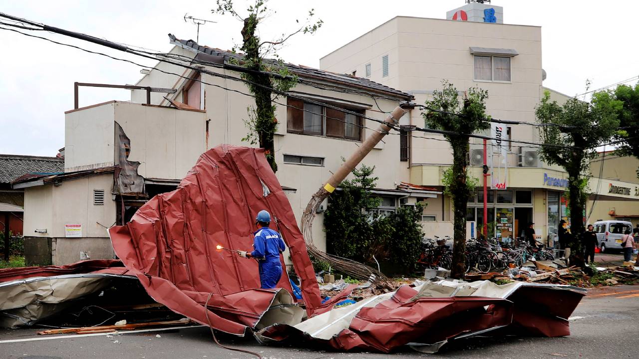 A worker removes debris blown away by strong winds caused by Typhoon Shanshan in Miyazaki on August 29, 2024. One of the strongest typhoons to hit Japan in decades dumped torrential rain across southern regions on August 29, with authorities warning of life-threatening flooding and landslides. (Photo by JIJI Press / AFP) / Japan OUT