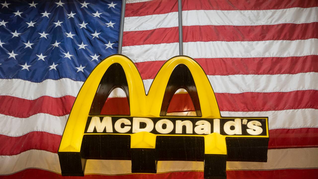 Logo do McDonald's em frente a uma bandeira americana na fachada da Broadway Avenue, em Nova York, EUA. 10/08/2023