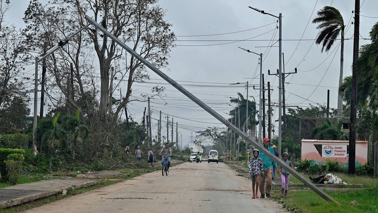 Moradores passam por árvores caídas e linhas de energia após a passagem do furacão Rafael em Artemisa, Cuba, em 7 de novembro de 2024