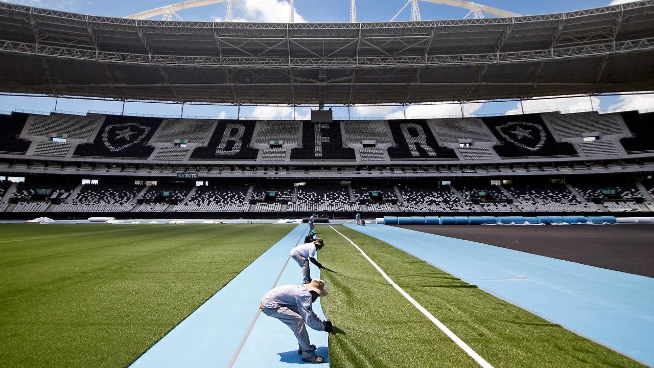 Funcionários da reforma do gramado do Estádio Nilton Santos trabalham no campo em março de 2023
