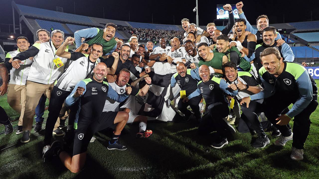 Jogadores e comissão técnica do Botafogo celebram a classificação para a final da Libertadores no Estádio Centenário, em Montevidéu, com a torcida ao fundo