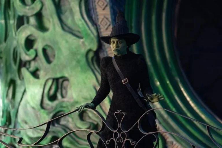 elphaba na cidade esmeralda Elphaba, de Cynthia Erivo: silhueta sóbria e padrão texturizado para vestidos de cintura marcada e chapéu símbolo da bruxa