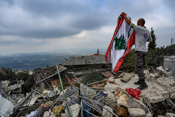 Cidadão libanês ergue a bandeira do Líbano em meio a destroços de ataque israelense na cidade de Deir Billa, Líbano. 13/10/2024