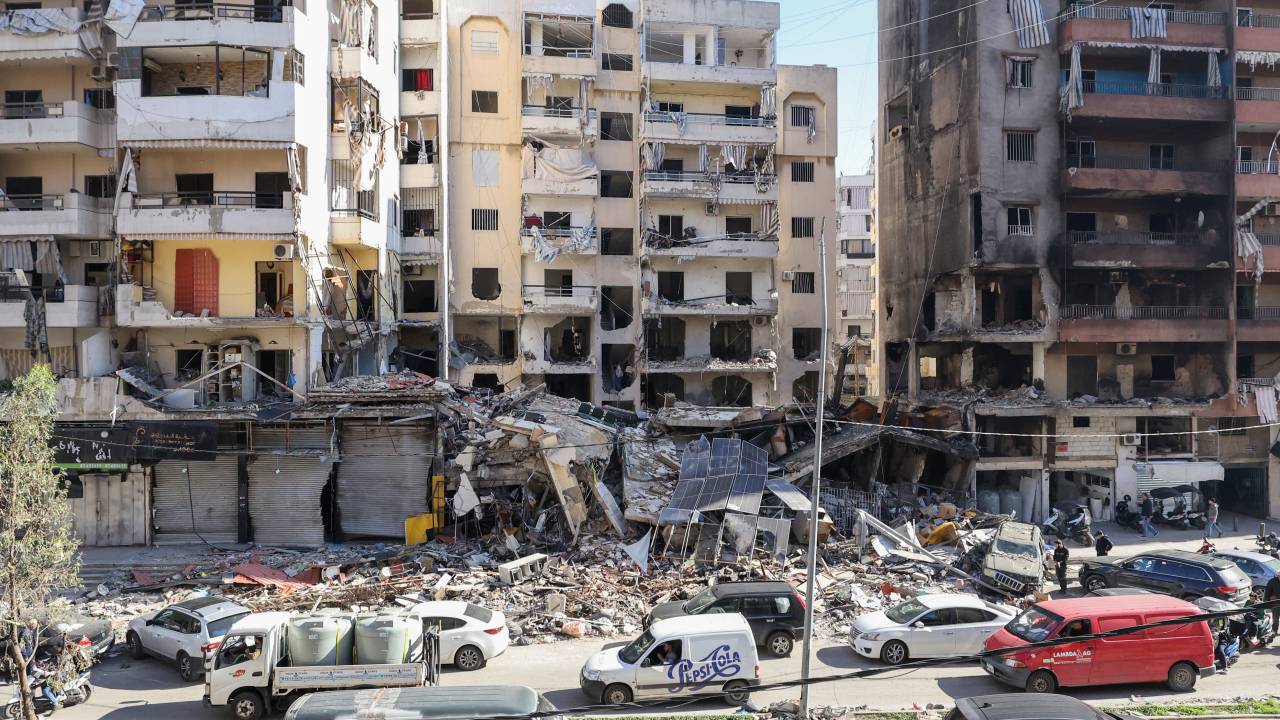 Cars drive past buildings that were damaged or destroyed in Israeli strikes in Beirut's southern suburbs Hay el-Sellom neighbourhood on December 2, 2024. (Photo by Anwar AMRO / AFP)