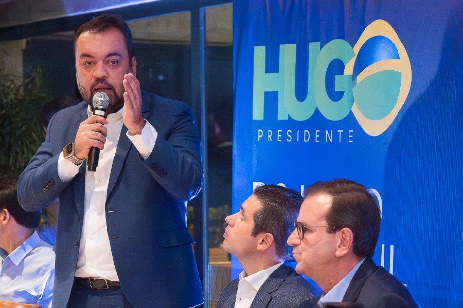 Castro discursa ao microfone em jantar em churrascaria no Rio, observado por Hugo Motta e Eduardo Paes