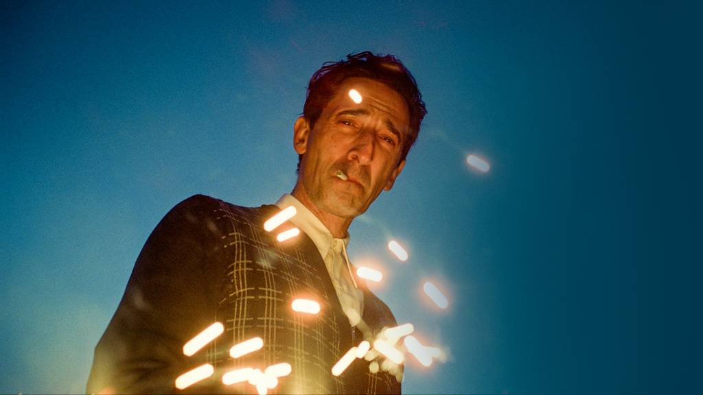 3—MV5BYzc2M2IwZTgtZTM2ZC00ODViLTg5MzItZTUyODRhOTk0YTI0XkEyXkFqcGc@._V1_.jpg 'O BRUTALISTA' - Protagonizado por Adrien Brody, o filme aplicou inteligência artificial em diálogos para corrigir erros de pronúncia e melhorar o sotaque do protagonista em cenas faladas em húngaro
