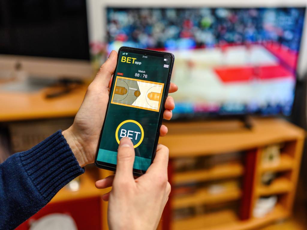 Young men using smart phone for sports betting.