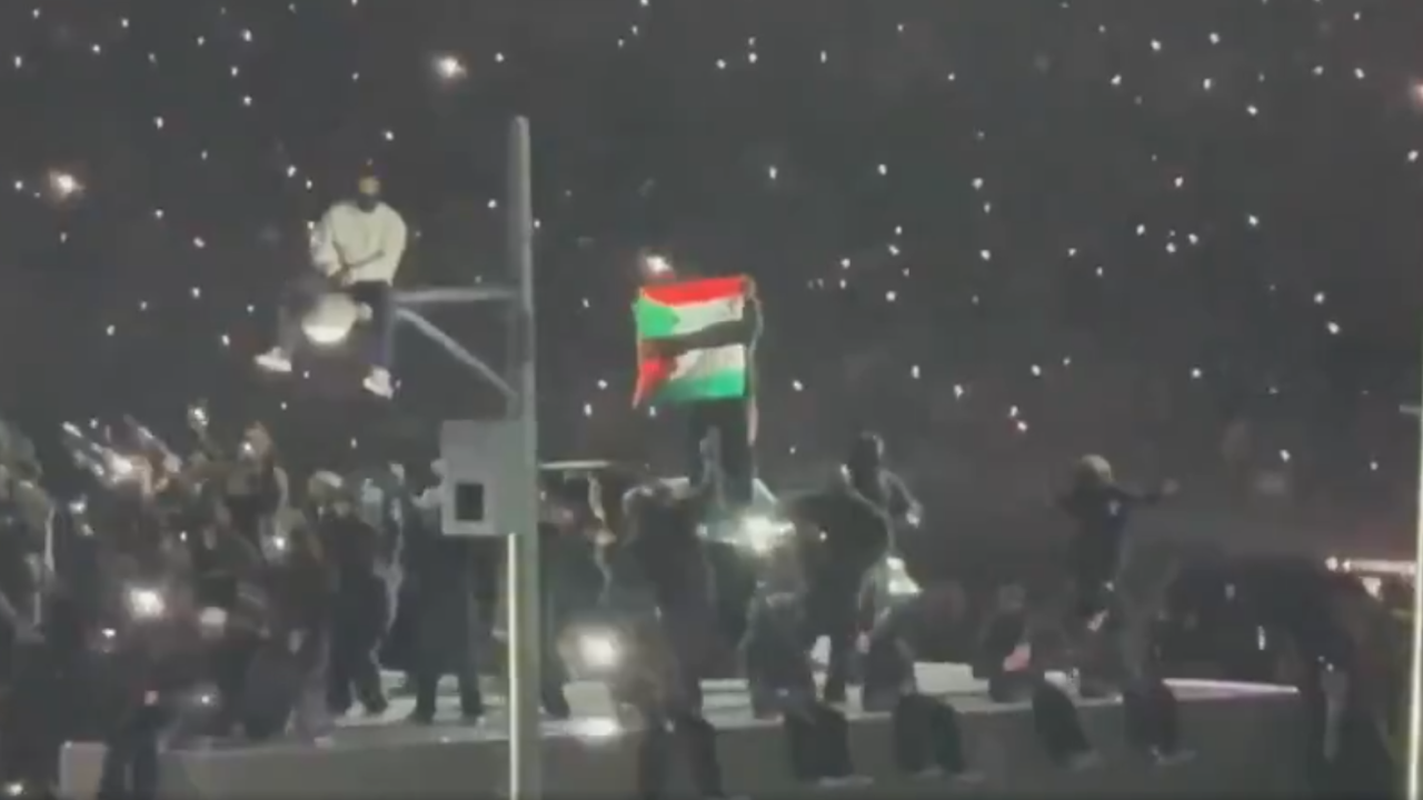 Manifestante exibe bandeira do Sudão e da Palestina durante o show de Kendrick Lanar, no intervalo do Super Bowl 2025