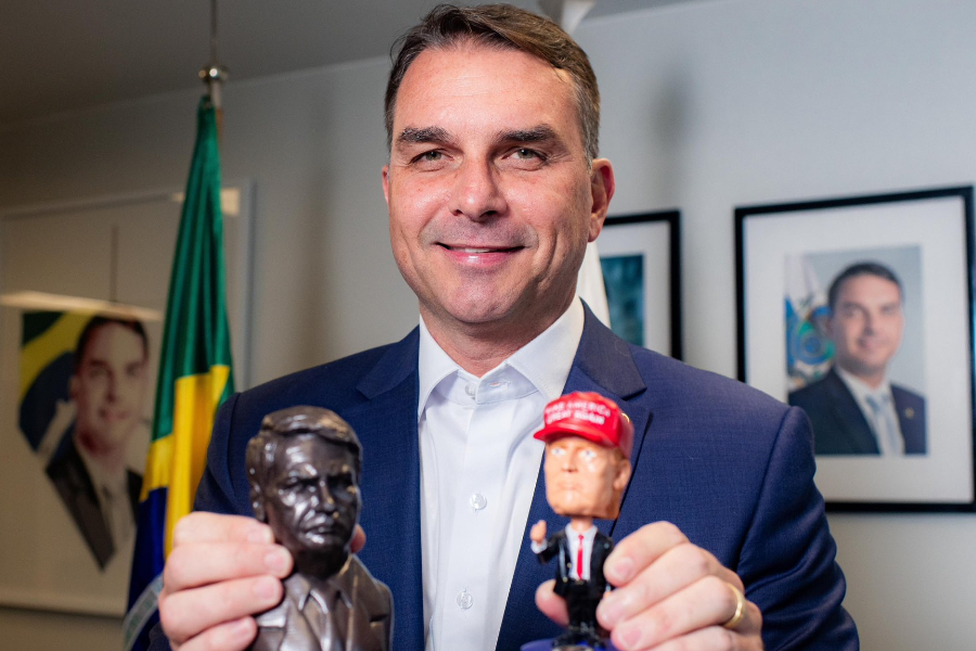 O senador Flávio Bolsonaro (PL-RJ) exibindo miniaturas do pai, o ex-presidente Jair Bolsonaro, e do presidente dos Estados Unidos, Donald Trump