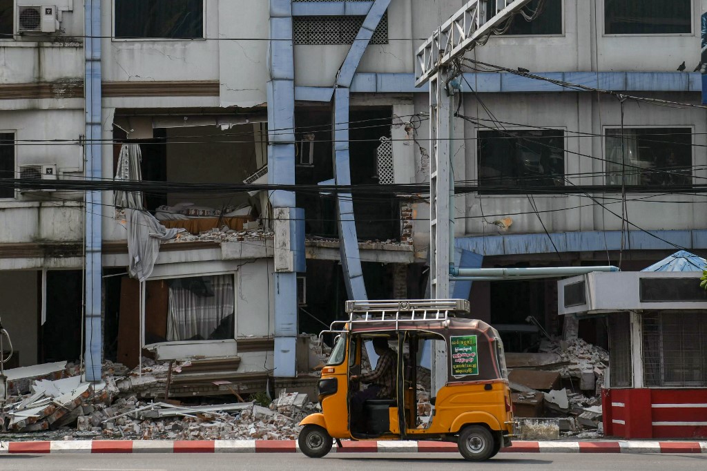 A tuk-tuk drives past a damaged building in Mandalay on March 29, 2025, a day after an earthquake struck central Myanmar. Rescuers dug through the rubble of collapsed buildings on March 29 in a desperate search for survivors after a huge earthquake hit Myanmar and Thailand, killing more than 1000 people. (Photo by Sai Aung MAIN / AFP)