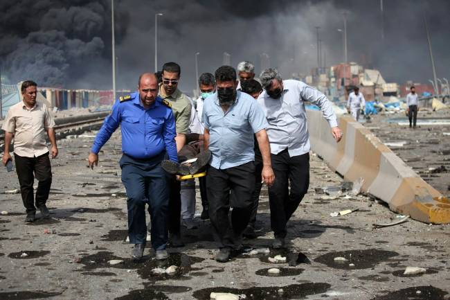 IRAN-PORT-EXPLOSION People transport an injured man along a devastated boulevard following an explosion at the Shahid Rajaee port dock southwest of Bandar Abbas in the Iranian province of Hormozgan on April 26, 2025. Several containers exploded on April 26 at Iran's largest commercial port, authorities said, causing a major blast and fire, and leaving hundreds injured. Shahid Rajaee, more than 1,000 kilometres (620 miles) south of the capital, is the most advanced container port in Iran, according to the official IRNA news agency. (Photo by MOHAMMAD RASOLE MORADI / IRNA / AFP)