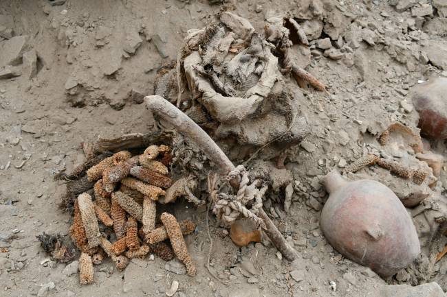 Peru tumulo coletivo Milho, cerâmica e tecidos foram encontrados junto aos corpos, indicando que os mortos foram sepultados com oferendas típicas de rituais funerários do período pré-incaico.