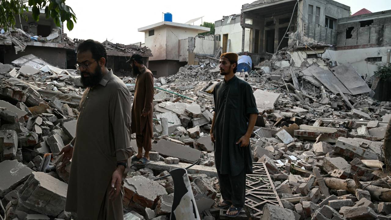 Locals stand on the debris of destroyed structures at the Government Health and Educational complex in Muridke about 30 kilometres from Lahore, on May 7, 2025, after Indian strikes. The death toll from Indian strikes on Pakistan has increased to eight, the country's military spokesman said on May 7, as India fired missiles at Pakistani territory and Islamabad vowed to "settle the score". (Photo by FAROOQ NAEEM / AFP)