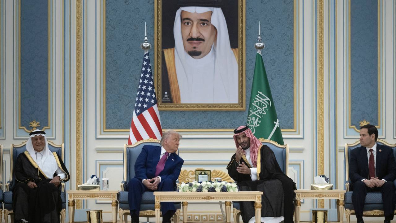 Seated under a portrait of Saudi Arabia's King Salman, US President Donald Trump and the kingdom's Crown Prince Mohammed Bin Salman (C) talk before a coffee ceremony at the Royal Court in Riyadh on May 13, 2025. Trump enjoyed a lavish, royal welcome in Saudi Arabia on the first state visit of his second term, with the US president foremost focused on business deals at the start of a Gulf tour. (Photo by Brendan Smialowski / AFP)