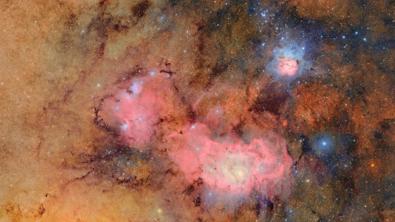Esta imagem combina 678 fotografias captadas pelo Observatório Vera C. Rubin, da NSF-DOE, em pouco mais de sete horas de observação. Ao juntar tantos registros, é possível revelar com clareza detalhes que seriam invisíveis ou muito tênues, como as nuvens de gás e poeira que compõem a nebulosa Trífida (no canto superior direito) e a nebulosa Lagoa, localizadas a milhares de anos-luz da Terra.