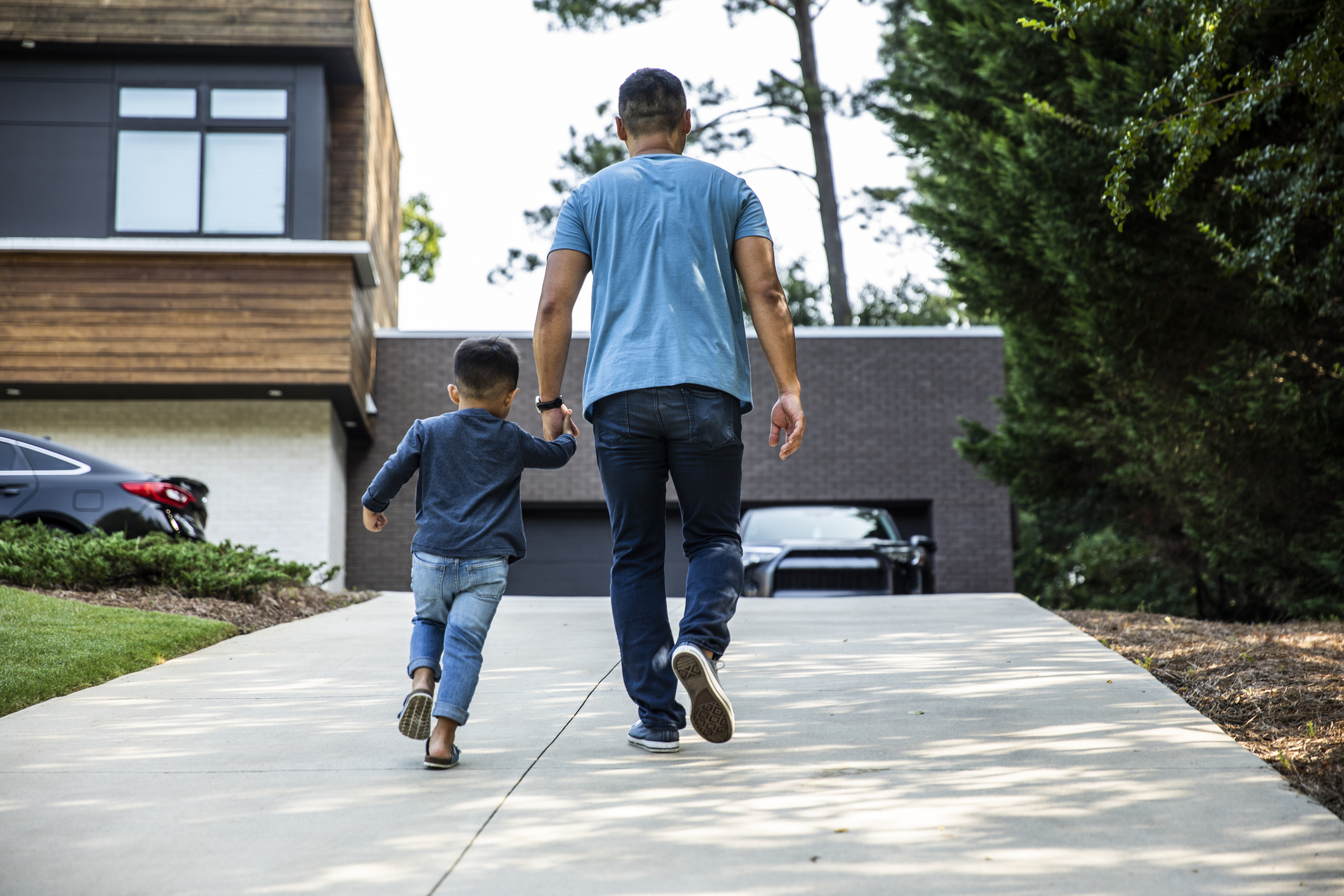 Father walking up driveway with son