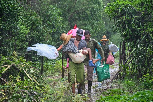 Residents self-evacuate under pouring rain from Playa Siboney to safe locations ahead of the arrival of Hurricane Melissa, in Santiago de Cuba, Cuba, on October 28, 2025. Hurricane Melissa was set to strike nearby eastern end of Cuba late Tuesday after pummeling Jamaica. (Photo by YAMIL LAGE / AFP)