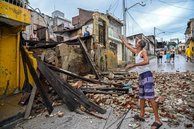 Residents inspect a house destroyed by Hurricane Melissa in a neighborhood of Santiago de Cuba on October 29, 2025. A powerful Hurricane Melissa made landfall in eastern Cuba on Wednesday, causing damage and flooding to homes and streets in Santiago de Cuba province, an AFP team on the ground reported. (Photo by YAMIL LAGE / AFP)