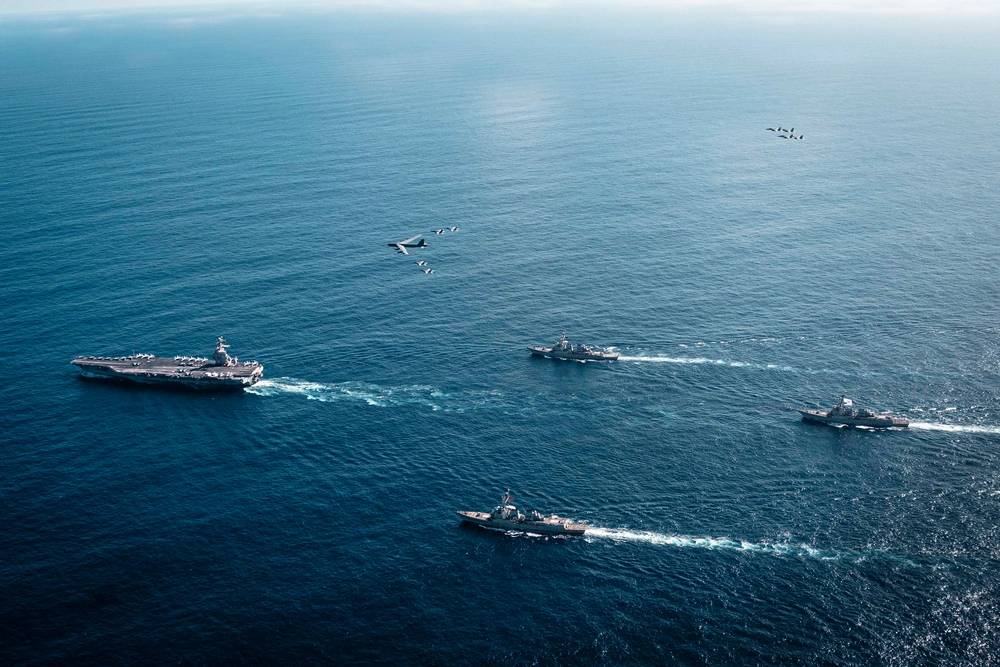 O Grupo de Ataque do Porta-Aviões Gerald R. Ford da Marinha dos EUA, incluindo o navio-almirante USS Gerald R. Ford (CVN 78), à esquerda, o USS Winston S. Churchill (DDG 81), à frente, o USS Mahan (DDG 72), atrás, o USS Bainbridge (DDG 96) e os caças F/A-18E/F Super Hornets embarcados.
