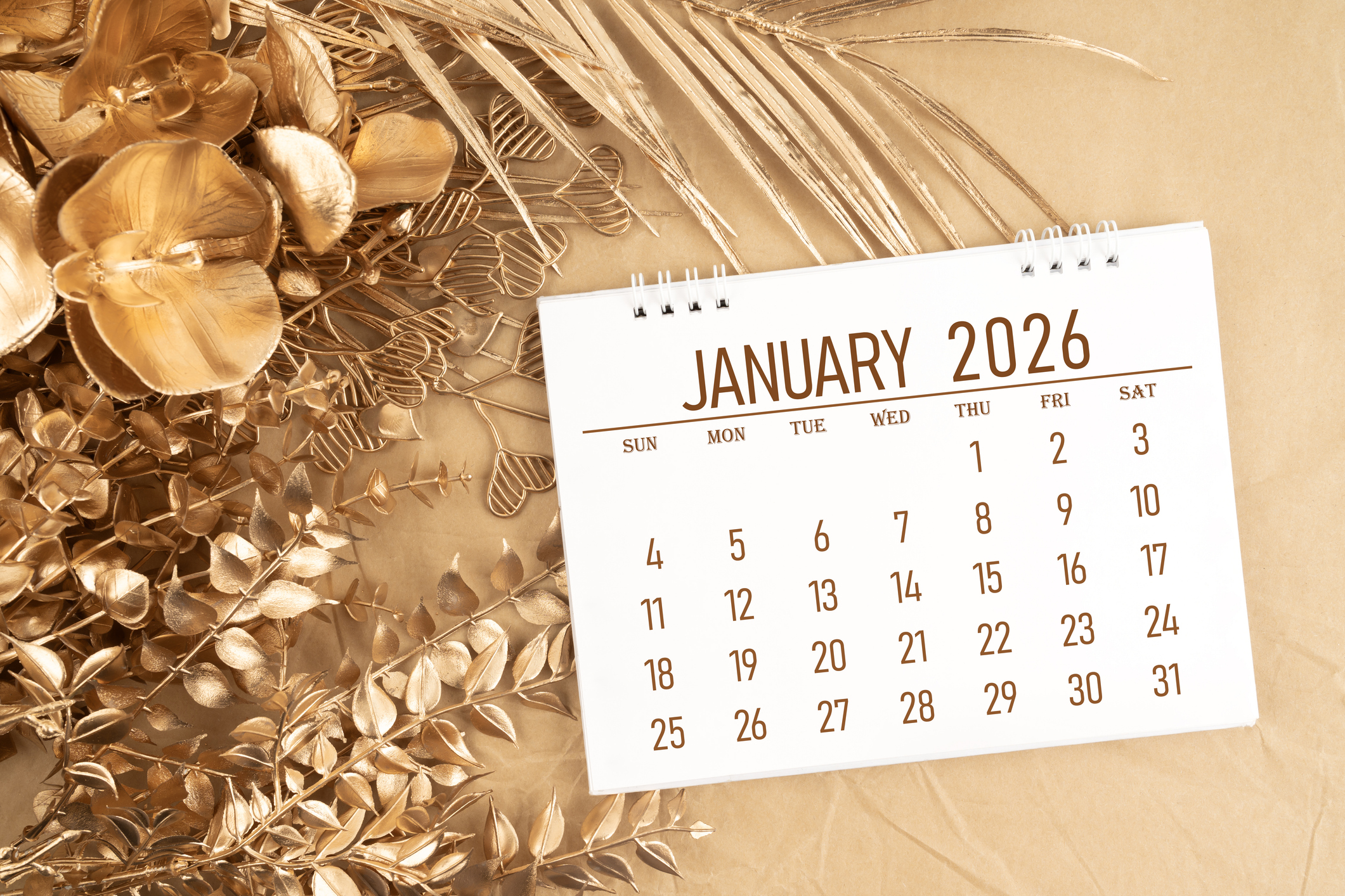 January 2026 desk calendar with golden flower and leaves on yellow color background, Flat lay.