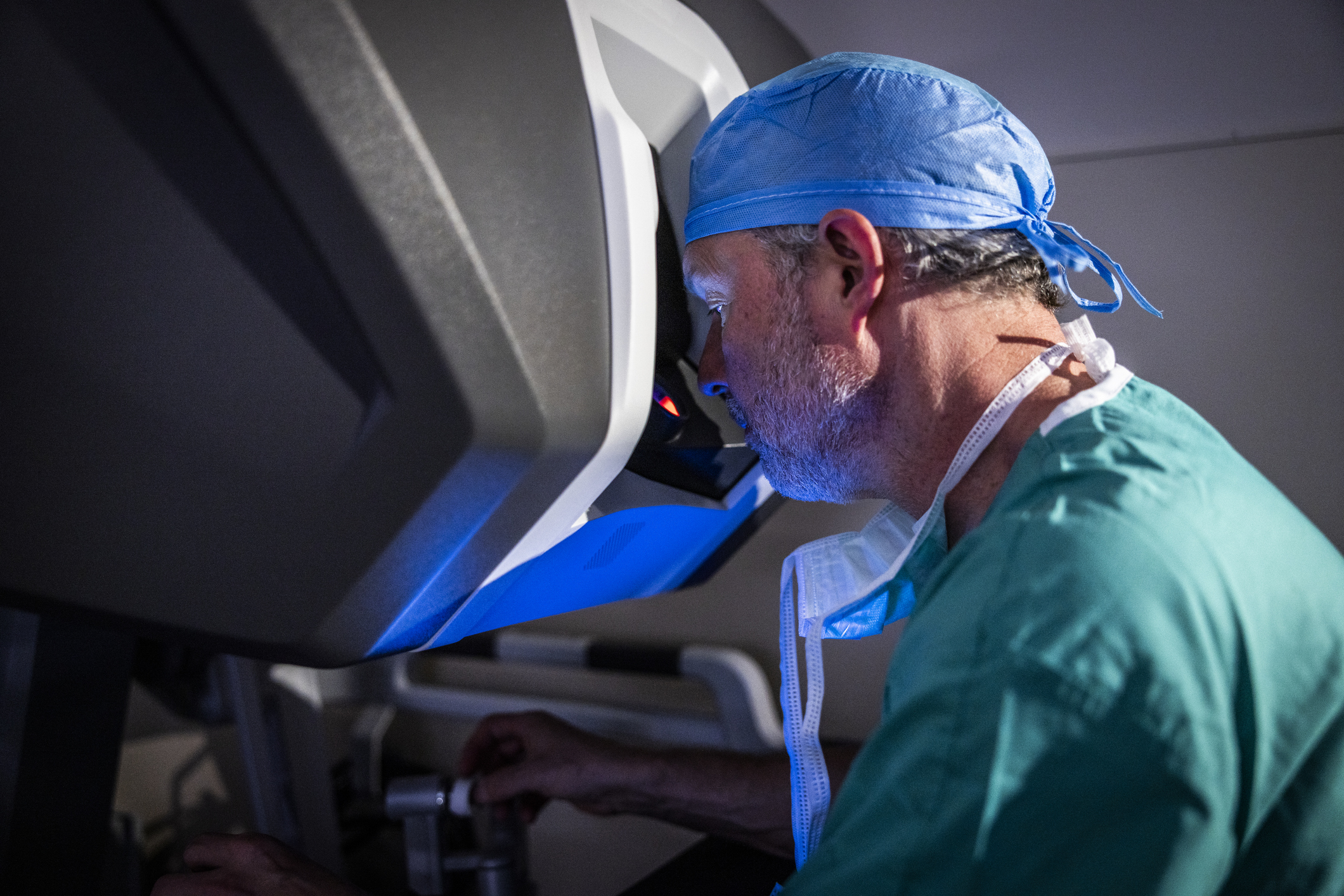 Male surgeon sitting at surgical robotic console