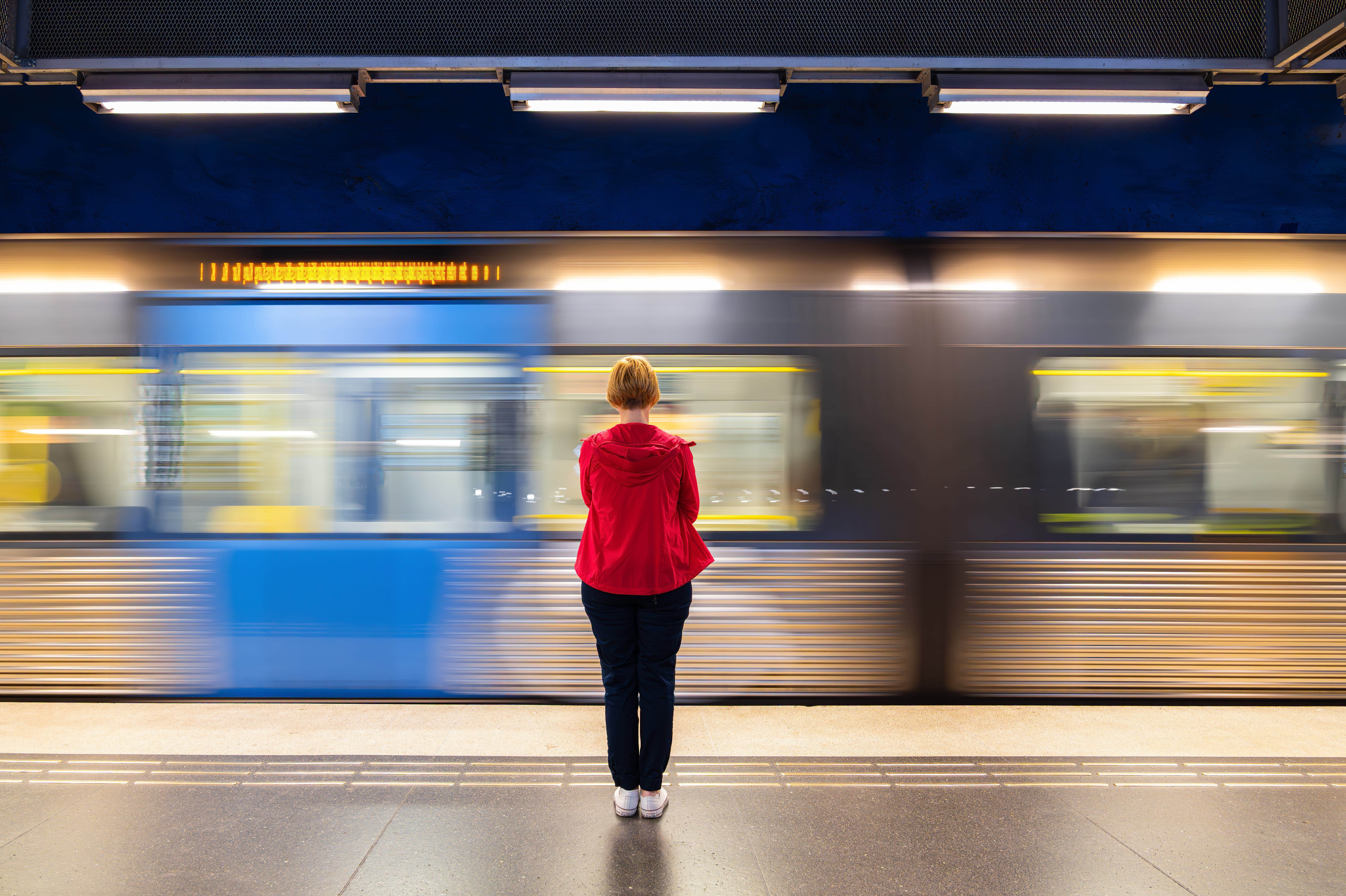 Woman Waiting at Subway Station in Stockholm with Train in Motion