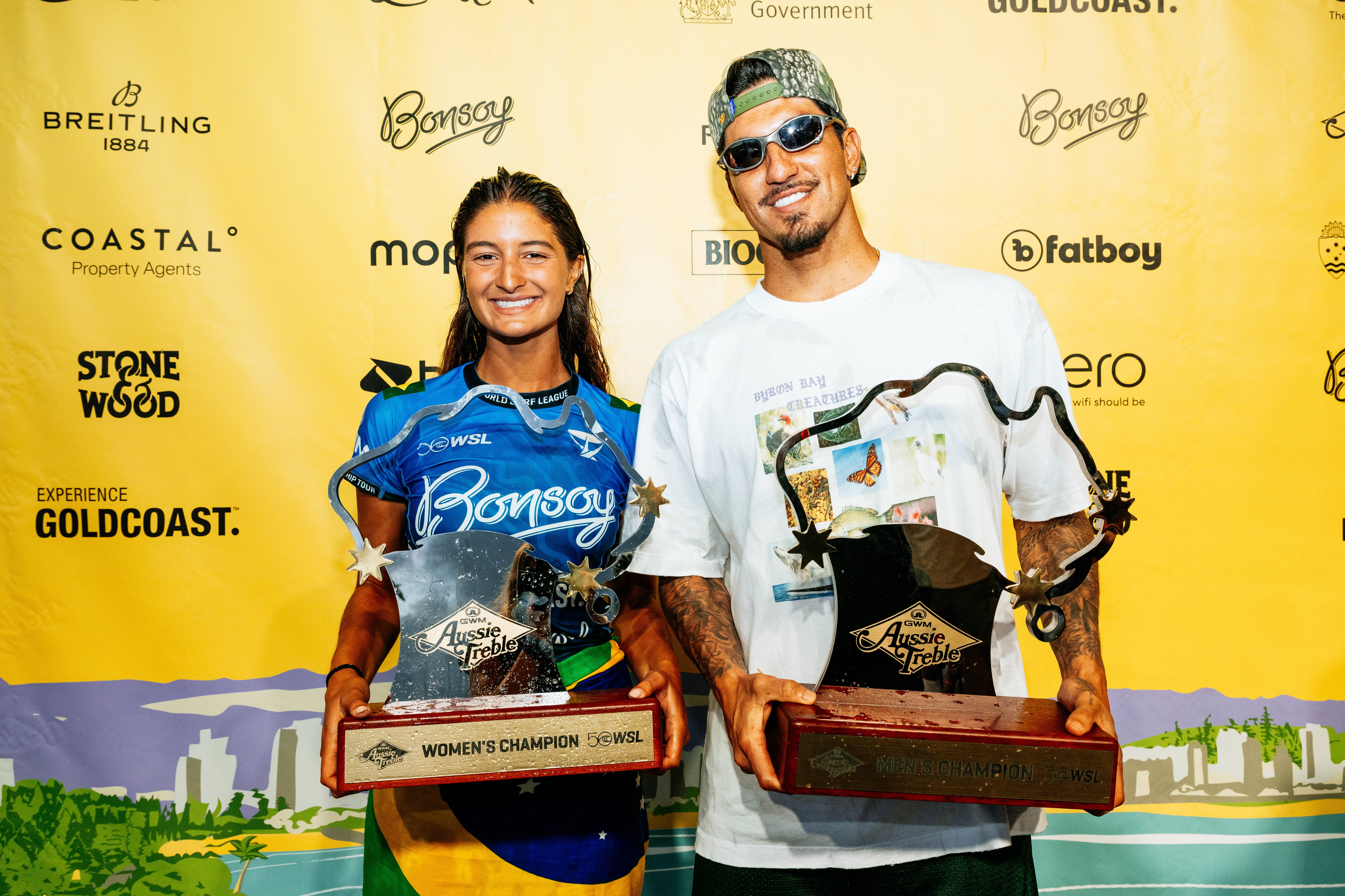 Foto de Gabriel Medina e Luana Silva segurando troféus da Coroa Australiana.