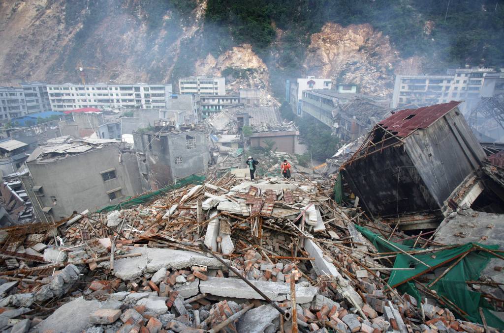 Sobreviventes de um terremoto caminham sobre os escombros de casas desabadas em busca de parentes, em 14 de maio de 2008, no condado de Beichuan, província de Sichuan, China