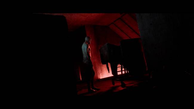Homem p&aacute;lido, de costas, em um ambiente escuro iluminado por uma luz vermelha intensa vinda do ch&atilde;o e do teto, com uma estrutura escura &agrave; direita